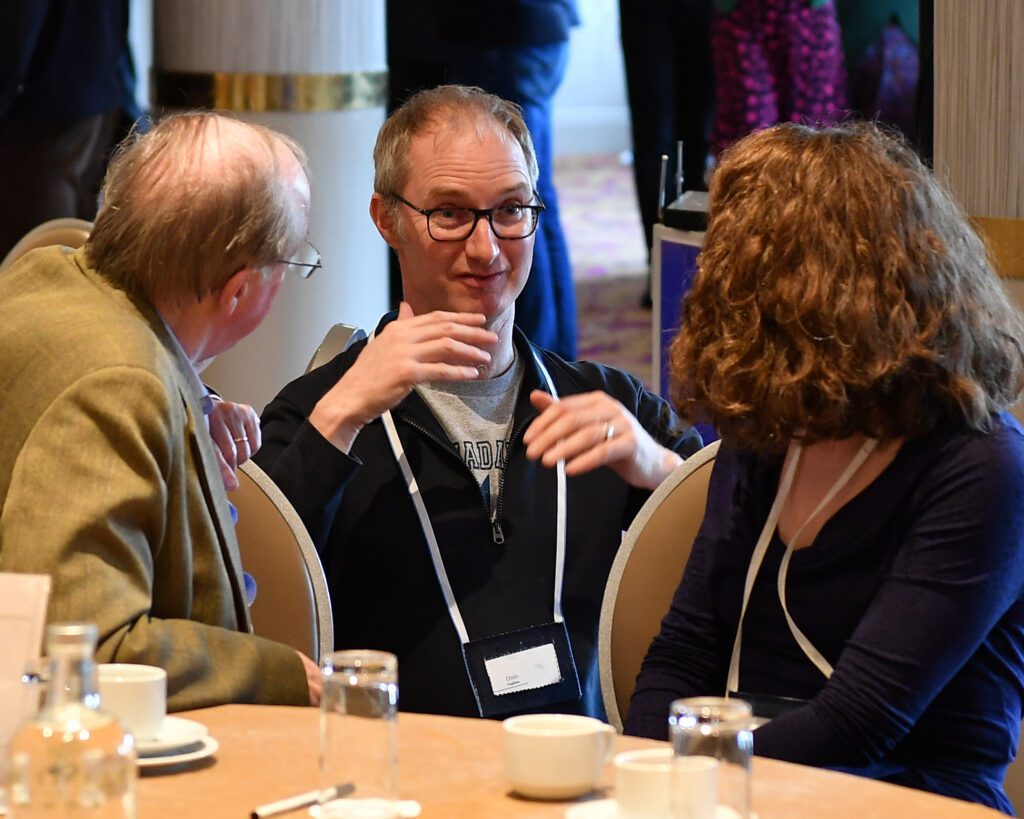 Photo of Oisin Coghlan in deep conversation with other attendees at the Community Foundation Ireland Convening on Climate.